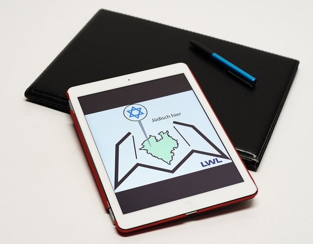 Ein Tablet, eine Mappe, ein Stift. Das Tablet zeigt das Logo von "Jüdisch hier" | LWL-Medienzentrum, Phillina Zuther