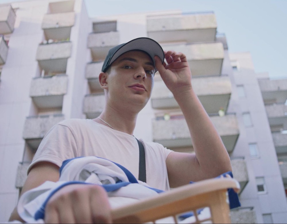 Filmstill aus "Masel Tov Cocktail", © SWR/Filmakademie Baden-Württemberg | Ein Jugendlicher mit einer Basballcap  grinst in die Kamera.